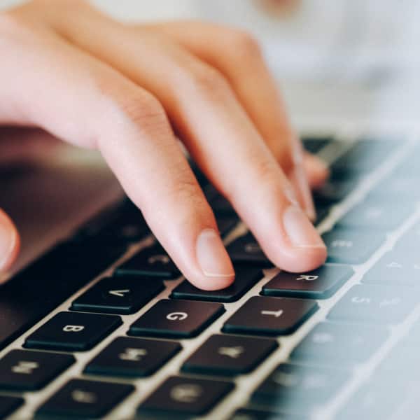 fingers typing on laptop keyboard for online banking services