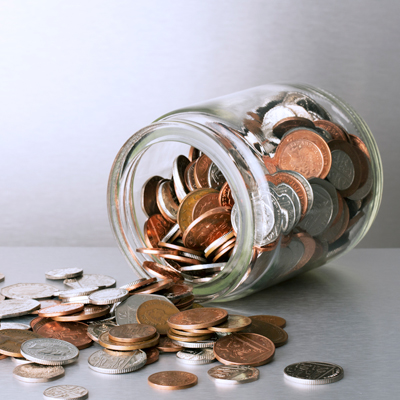 a glass jar pouring out coins