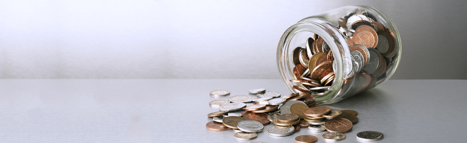 a jar with coins pouring out on the metalic table