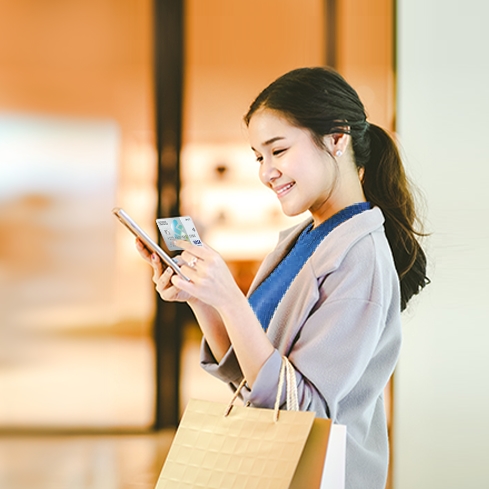 女士愉快地購物中及手持渣打Smart卡