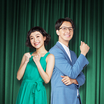 身穿天藍色西裝外套的男士及身穿綠色連身裙的女士微笑地擺姿勢，圖片用於推廣渣打分期貸款加借服務