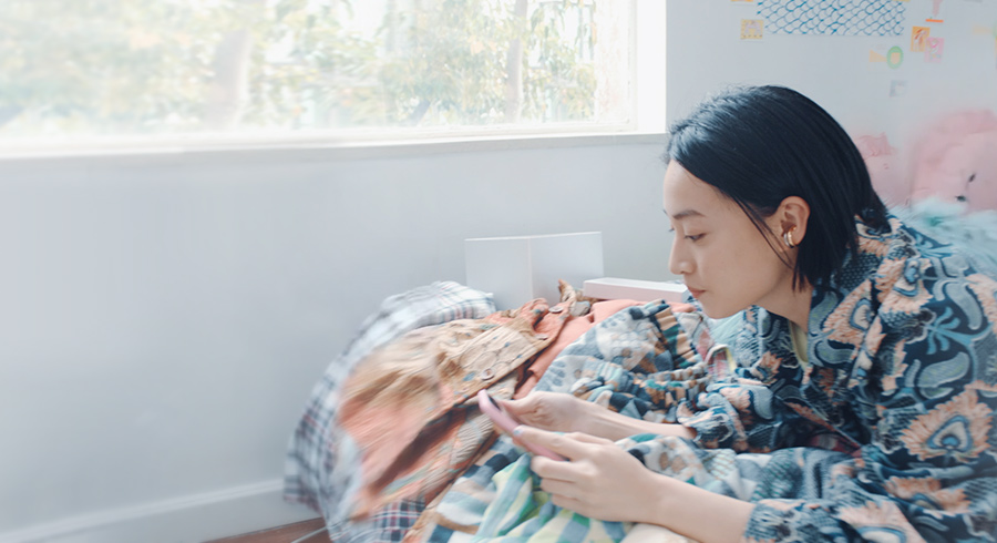 A lady using phone on bed